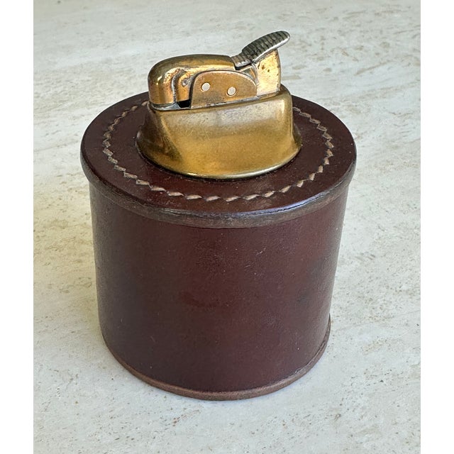 Vintage stitched leather table lighter with great patina. It needs fluid and does not currently light, but it works...