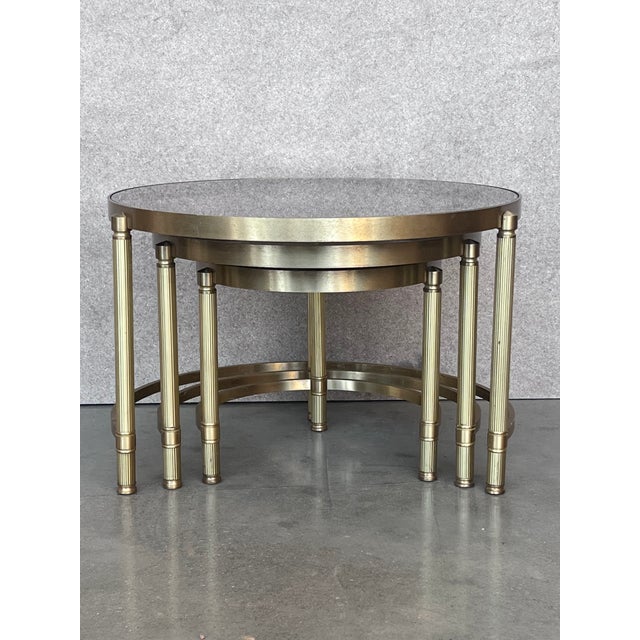 Set of three round brass nesting tables with decorative details and smoked glass tops. Measures: Small 14.75" diameter x...