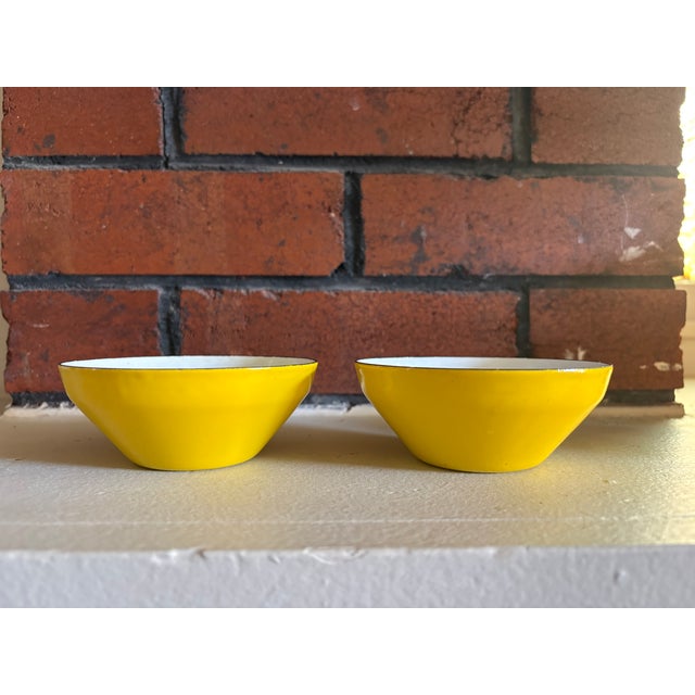 Cheerful pair of vintage enamel bowls in a vibrant yellow finish with white interiors. Classic mid-century form with...
