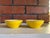 Cheerful pair of vintage enamel bowls in a vibrant yellow finish with white interiors. Classic mid-century form with...