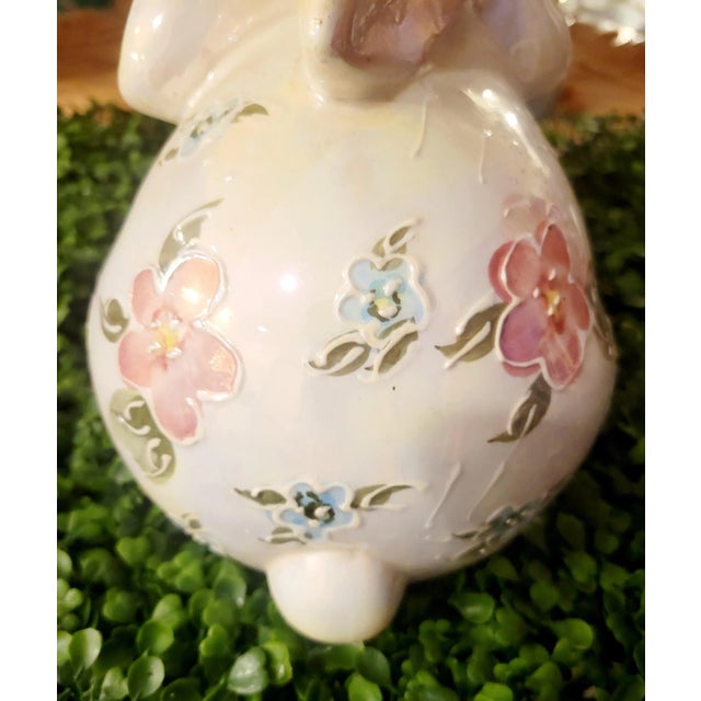 A sweet little ceramic bunny rabbit statue with raised floral design. The rabbit has a pearlized finish and on the side it...