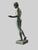 A classical bronze sculpture depicting an idealized nude male figure rendered in a graceful contrapposto stance, with...