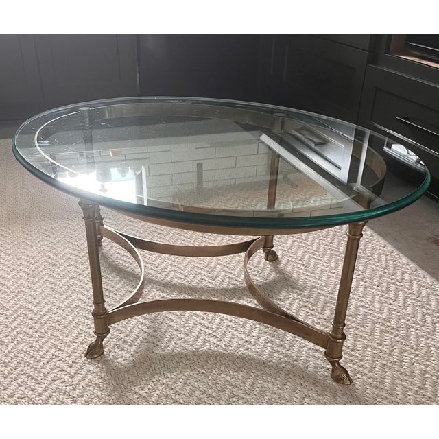 A gorgeous sleek Italian brass and heavy beveled glass oval cocktail table with sweet hooved feet unmarked, but in the...