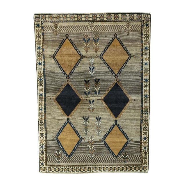This unique hand-knotted Gabbeh vintage rug impresses with its striking, geometric design and warm natural tones in brown,...