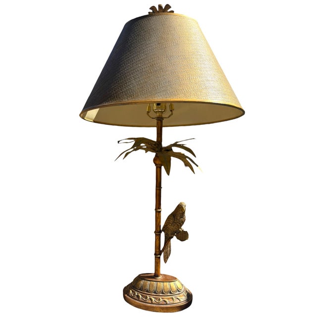 This striking sculptural table lamp features a detailed tropical bird perched alongside a tall palm tree, surrounded by...