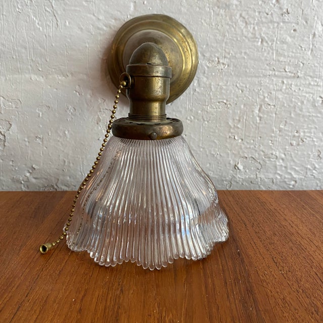 Dating from the early 20th century, this industrial wall sconce features a brass pipe arm with a beautiful time-earned...