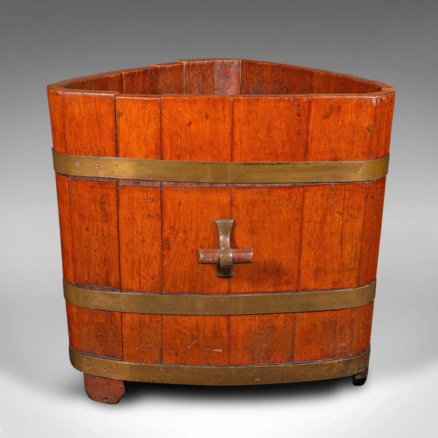 This is an antique triangular fireside bin. An English, walnut and brass coopered log store, dating to the early Victorian...