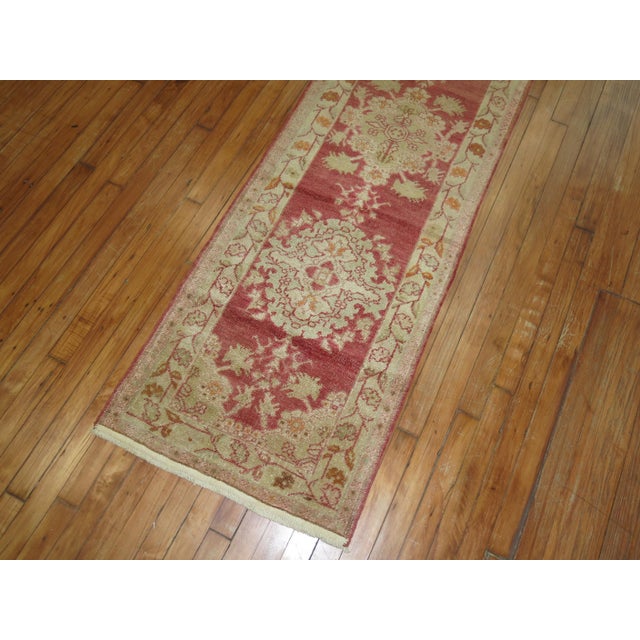 Mid-20th century red field Turkish runner with an all-over repetitive medallion design. Measures: 2'1” x 11'9”.