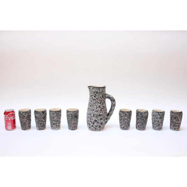 Heavily textured ceramic nine-piece drink serving set including eight cups/tumblers and a single pitcher (ca. 1960s,...