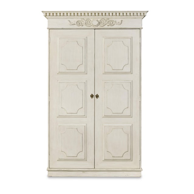 The 19th-century inspired wardrobe featuring a neoclassical dental molding cornice and raised panel doors reflects the...