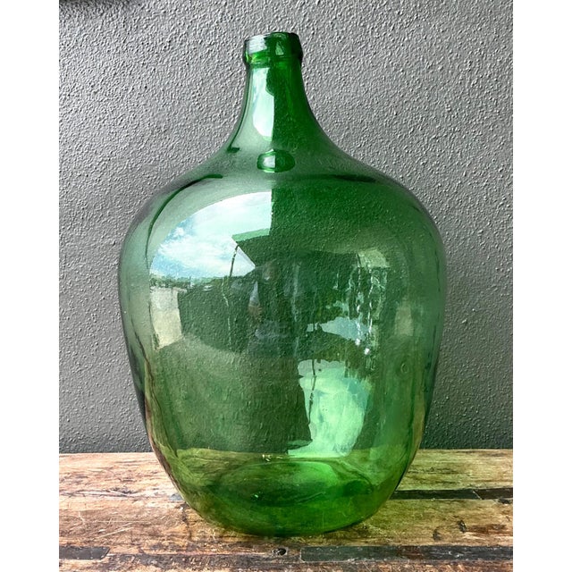 This vintage green glass demijohn bottle is a striking example of mid-20th-century utilitarian glassware, prized today for...