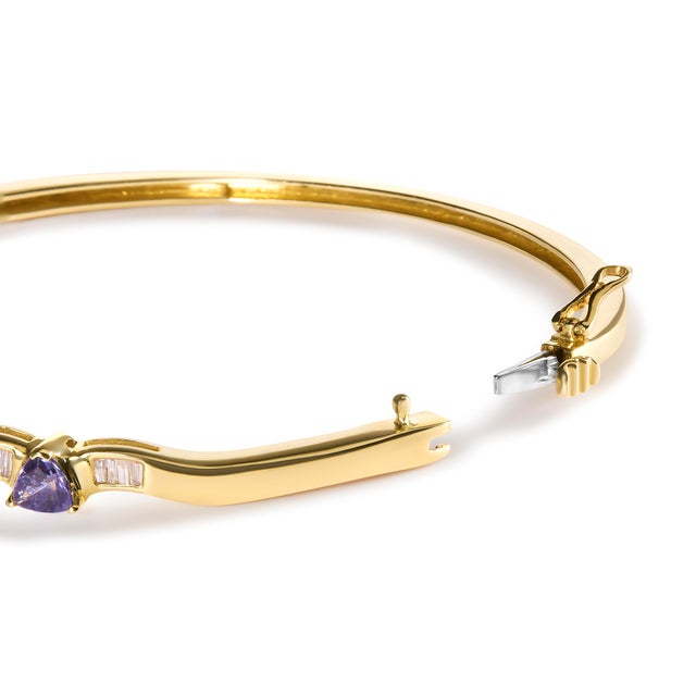 Immerse yourself in the exquisite elegance of this 14K yellow gold bangle, intricately crafted with alternating trillion...