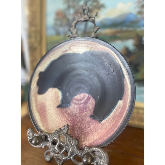 This handcrafted ceramic plate features a striking silhouette of a bear rendered in deep black glaze against a background...