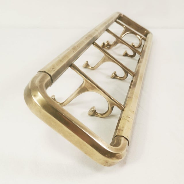 Wall-mounted coat rack, Austrian 1940s. Made of brass, it has four double swivel hooks. It has a minimalist yet decorative...