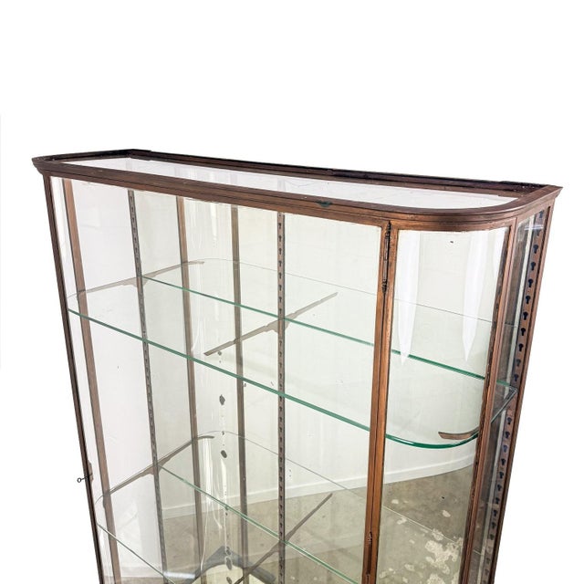 Impressive large antique museum display cabinet featuring elegant curved glass panels and a beautifully aged bronze-...