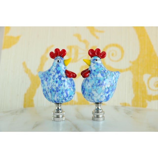 Pair of lamp finials crafted from speckled glass roosters mounted on knurled chrome finial bases sized to fit a standard-...
