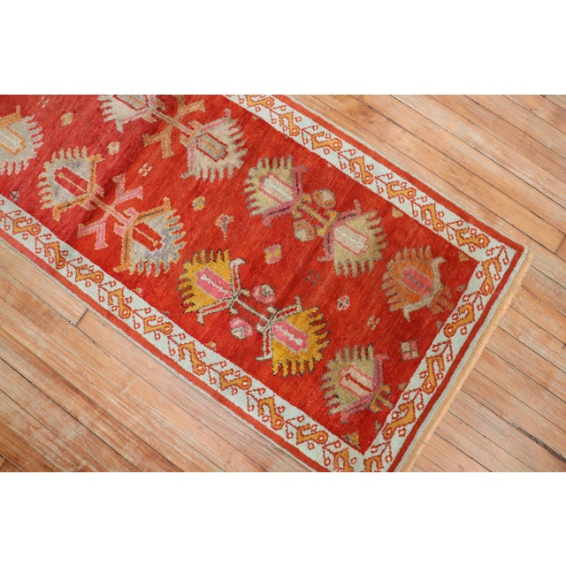 An early 20th century narrow and short antique oushak runner in red. Measures: 2'5'' x 6'6''.