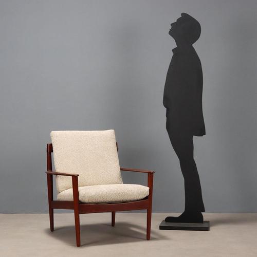 Vintage armchair with exposed teak wood frame, newly renovated cushions with sand-colored bouclé fabric that rest on...