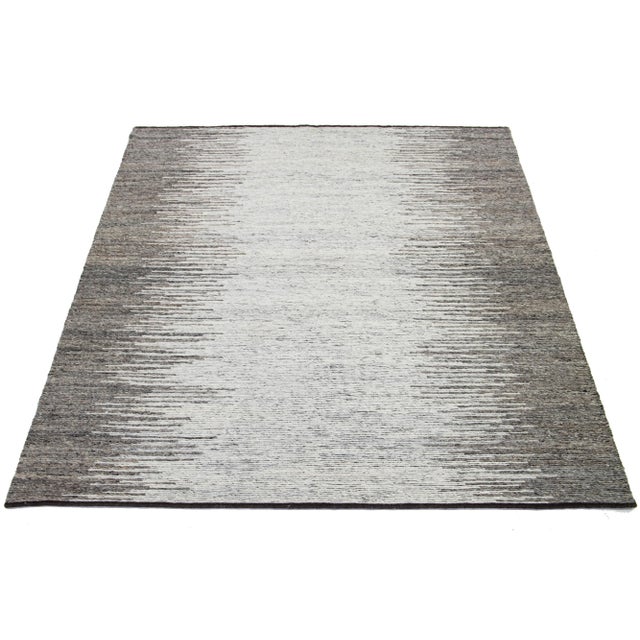 This Modern hand-knotted wool rug showcases a stunning Ivory and gray field with an all-over geometric abstract design....