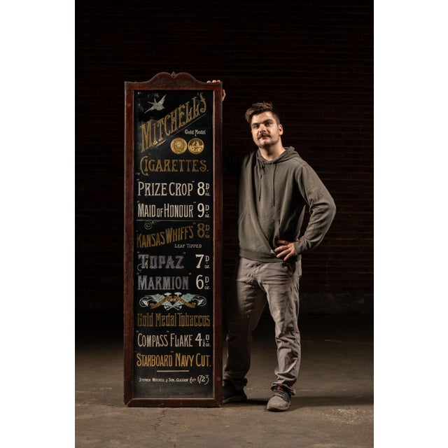 This tall turn-of-the-century reverse-painted glass advertising sign features richly rendered gold-leaf lettering...