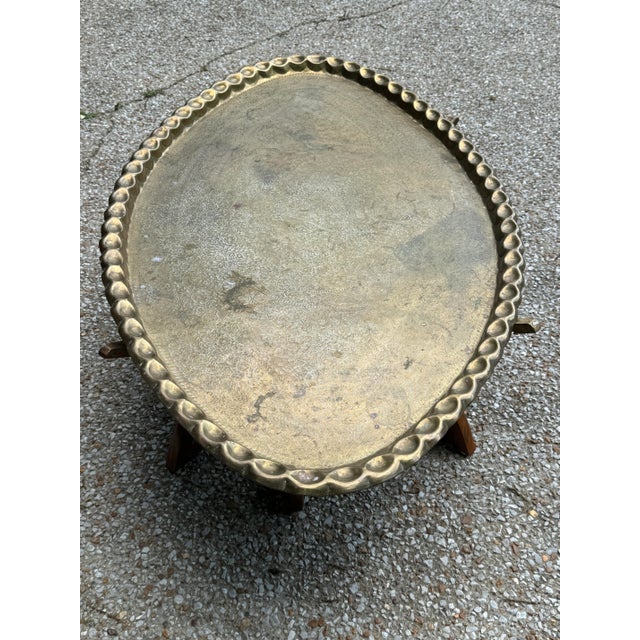 This is a gorgeous moroccan mid century brass coffee table. The materials are a solid brass top with wooden spider legs....