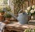 A beautifully weathered galvanized steel watering can dating to the 1940s, featuring a gracefully arched copper handle,...
