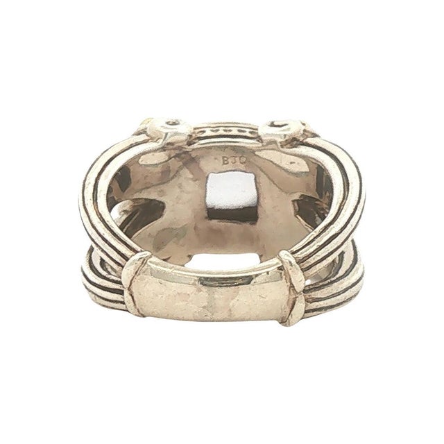 A striking contemporary fashion ring featuring a blue chalcedony cabochon. The stone is set in a bold design with 18k gold...