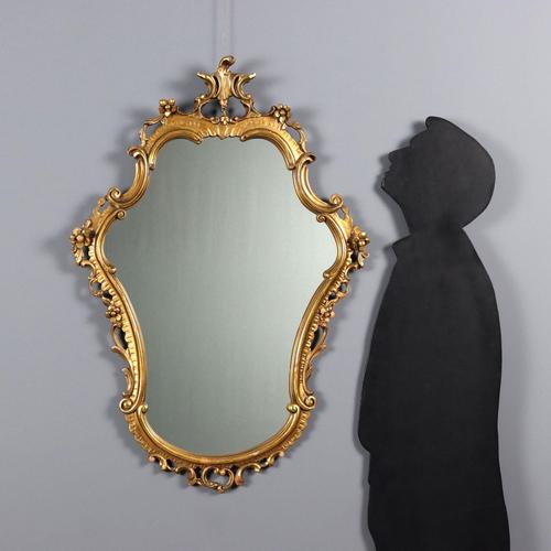 A carved and gilded late Baroque mirror. Floral, leafy, and scroll carvings throughout, with some gilding missing. Italy,...