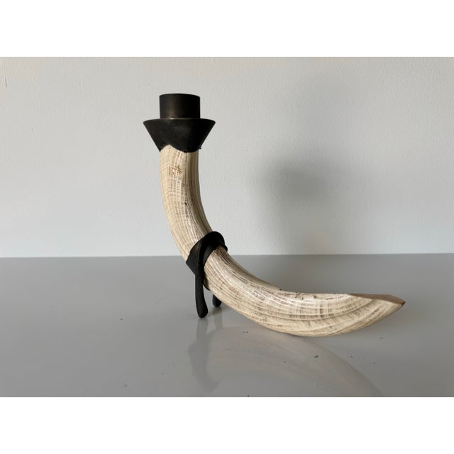 A sculptural vintage candle holder crafted from faux tusk resin, designed to mimic the look of natural ivory with rich...