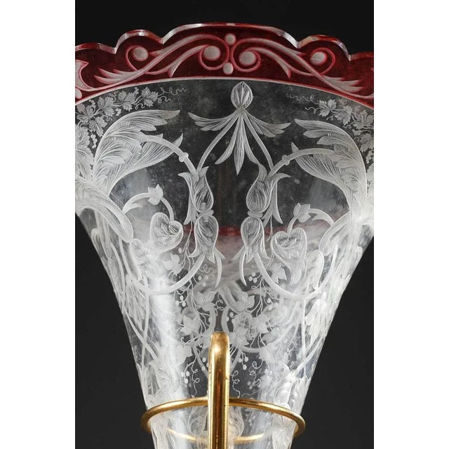 Red and transparent crystal centerpiece composed of a flared vase and cup. They are engraved with leafy rinceau, grape...