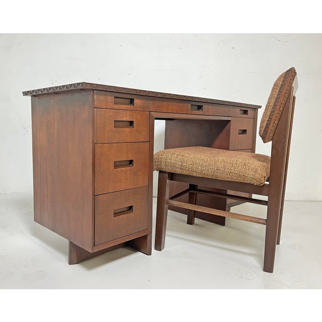 A mahogany writing desk and chair designed by Frank Lloyd Wright as part of his collaboration with Heritage Henredon in...