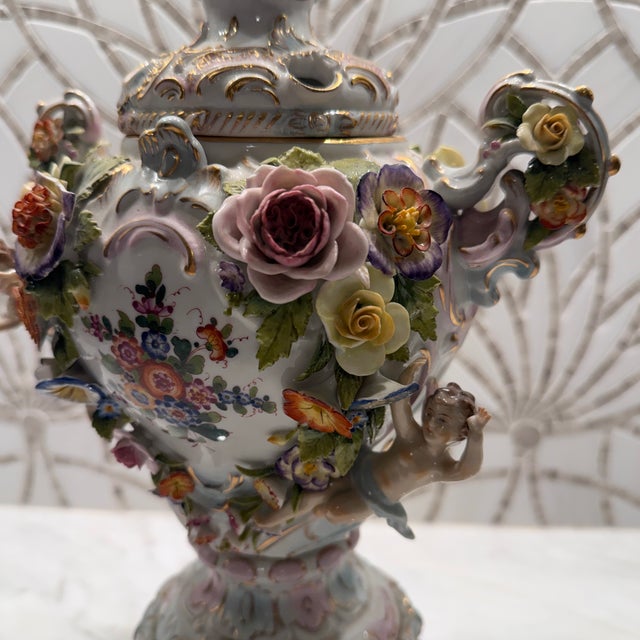 Dresden Porcelain in the Meissen style. A few small chips off flowers. One of cherub’s arm was glued back on and is...
