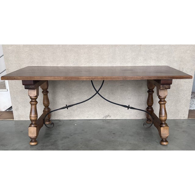 A Spanish Fratino dining table with hand made wrought-iron stretcher from the late 19th century. This Spanish wooden table...
