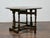 An English oak drop-leaf gateleg table from the 19th century, showcasing a rich, dark finish and a practical design rooted...