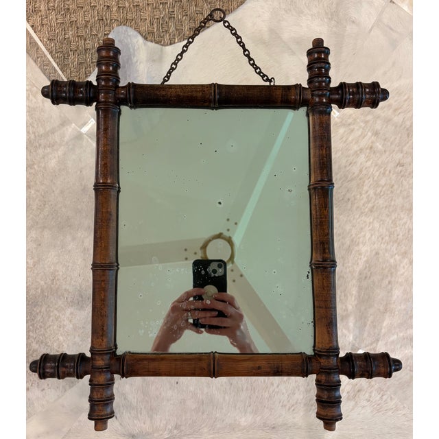 A charming antique French wall mirror featuring turned faux bamboo frame in darkened wood. The sculptural joinery mimics...