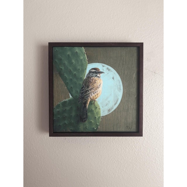 This oil painting features a Cactus Wren perched on a cactus, set against a softly illuminated moonlit background. The...
