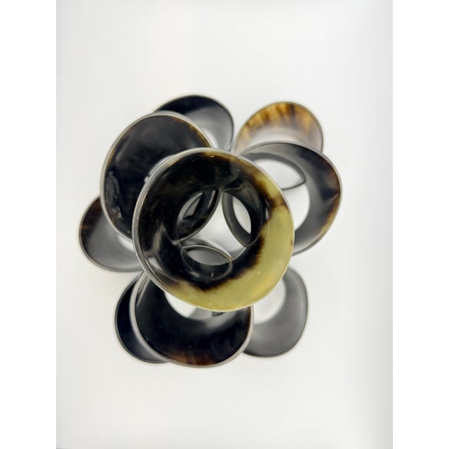 A sculptural set of ten hand-carved napkin rings crafted from natural horn, showcasing rich variations of charcoal, amber,...