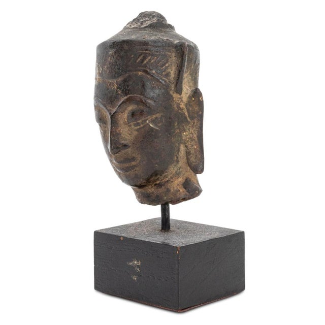 Thai Patinated Metal Buddha Head in Headdress, ebonized wood square base. Overall: 3" H x 1.5" W x 1" D. Provenance: From...