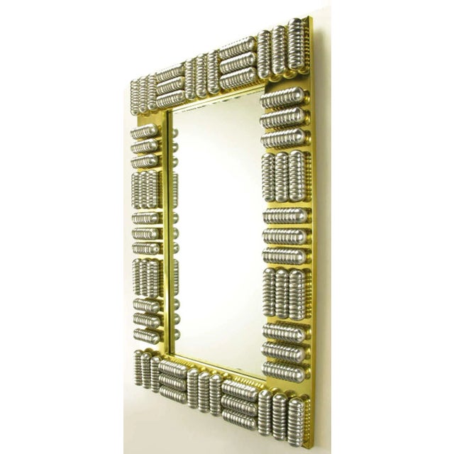 Custom made wall mirror with brass wrapped wood frame and a series of polished and ribbed aluminum enclosed tubes. Each...