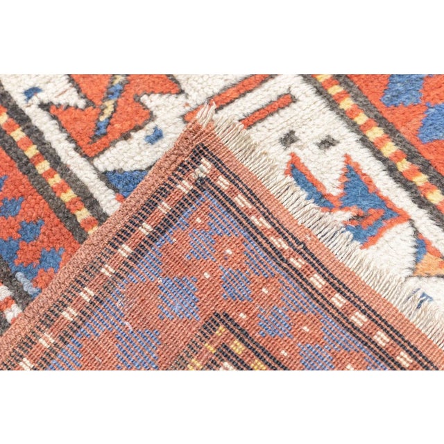 This thick pile, moderately coarsely woven SW Caucasian scatter presents seven rust and ecru hooked diamonds on an...