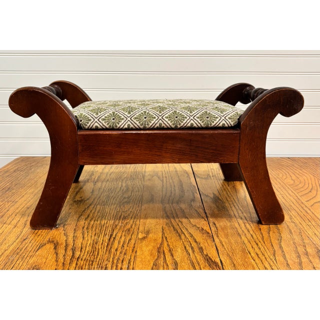 Vintage early American style foot stool featuring turned wood posts, flared legs and a seat upholstered in heavy woven...
