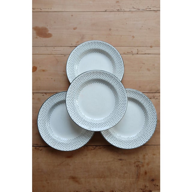Four Gien earthenware dinner plates, decorated with an elegant black polka dot border on an ivory background with a thin...