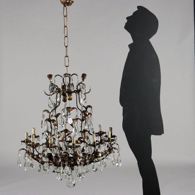 12 -light chandelier, in metal and a splaced and worked blade with foliage motifs; Golden, it is adorned with glass...