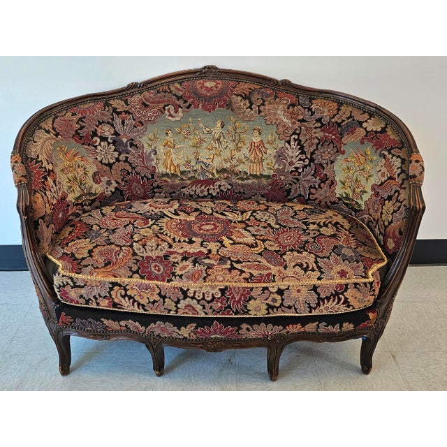 A French Louis XV style Settee features walnut frame with carved foliate, floral and scroll decoration; upholstered in...