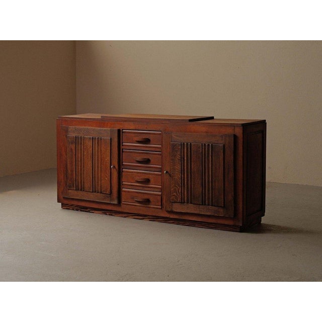 Crafted from solid oak and oak veneer, this French sideboard from the 1940s features two side cabinets flanking a central...