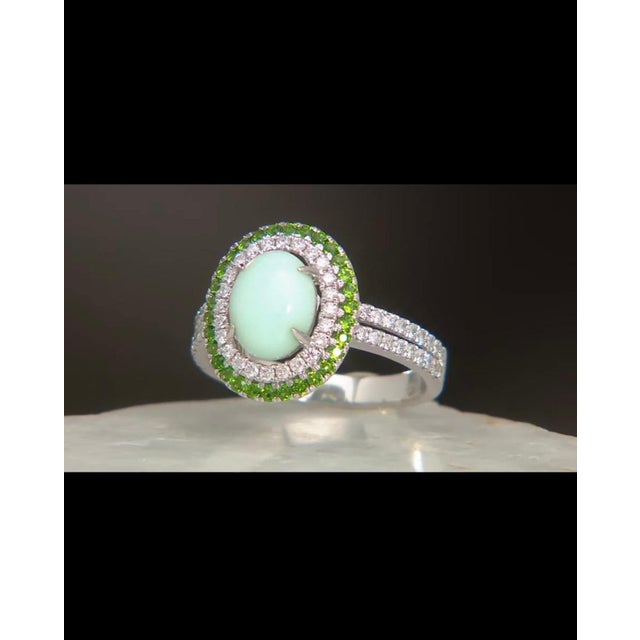 A vintage 14K white gold cocktail ring featuring a green opal cabochon at its center, encircled by a vivid halo of chrome...