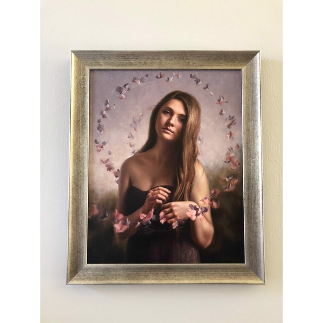In "Serenity," a young woman gazes softly at the viewer, surrounded by a delicate swirl of pastel butterflies that evoke a...