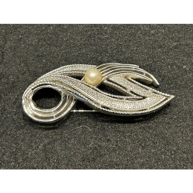 Elegant vintage brooch featuring a stylized leaf design, partially textured, while other areas are smooth and shiny,...