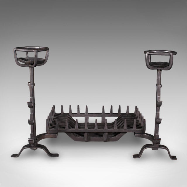 This is an antique fireplace set. An English, cast iron fire basket and mulling andirons, dating to the Georgian period,...