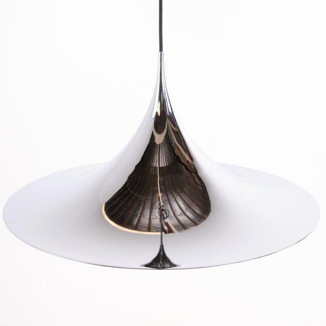 Semi / trumpet pendant designed by claus bonderup & torsten thorup. The lamp is finished in chrome and features the wide,...